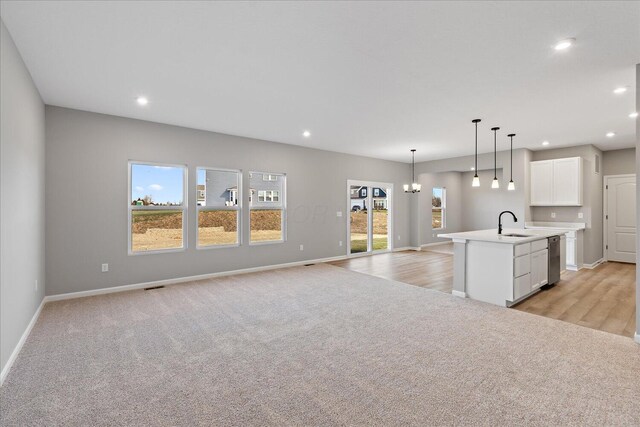 kitchen with a center island with sink, sink, decorative light fixtures, white cabinetry, and a chandelier