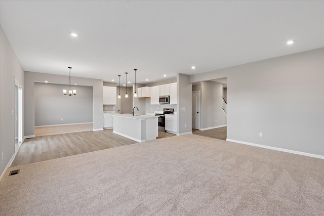 unfurnished living room with sink, light carpet, and a chandelier