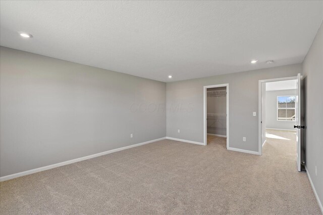 unfurnished bedroom featuring a spacious closet, a closet, and light carpet