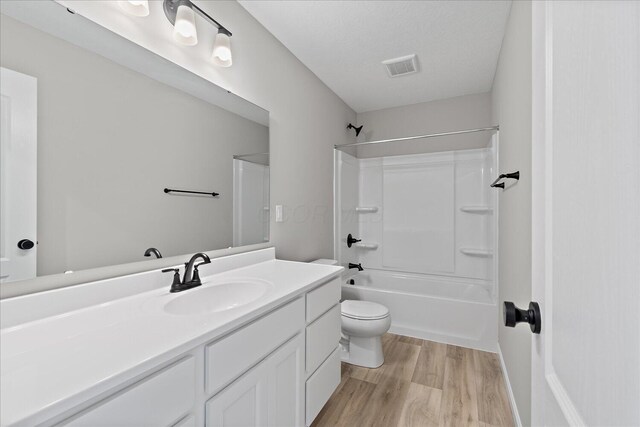 full bathroom featuring vanity, a textured ceiling, shower / tub combination, hardwood / wood-style floors, and toilet