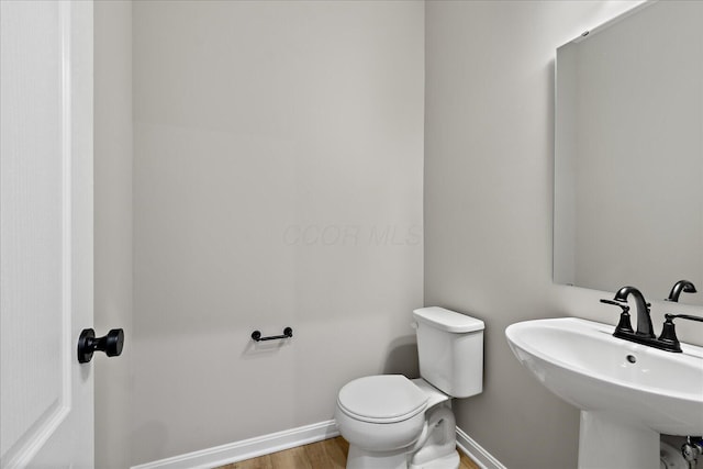 bathroom featuring toilet, hardwood / wood-style floors, and sink