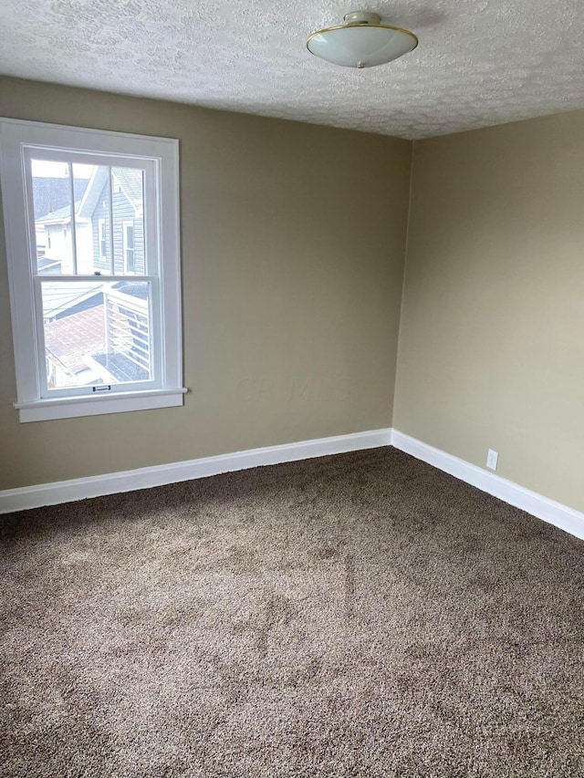 carpeted empty room featuring a textured ceiling