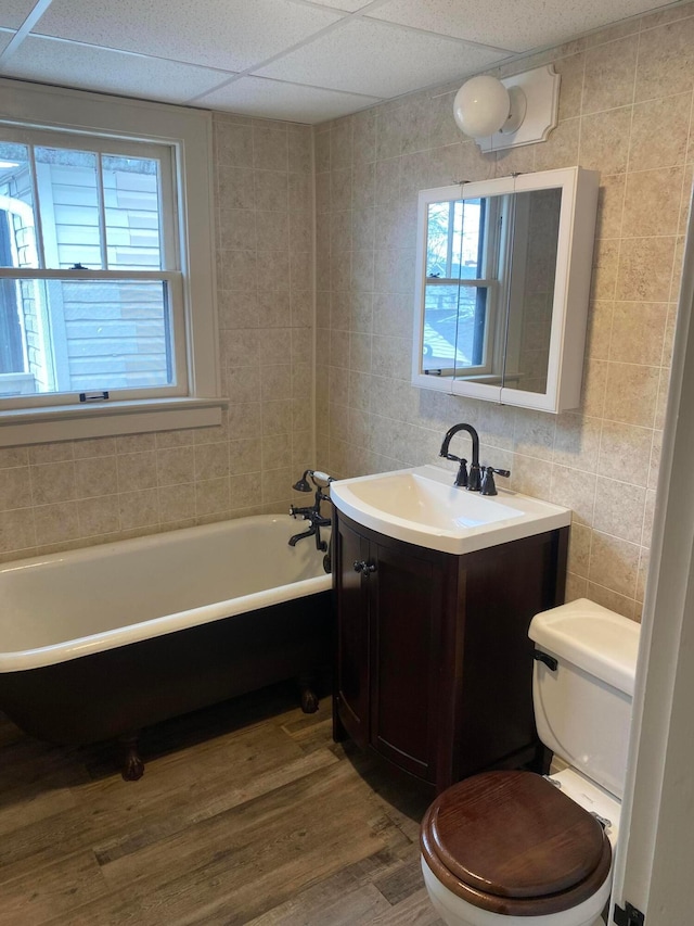 bathroom with hardwood / wood-style floors, a drop ceiling, toilet, and tile walls