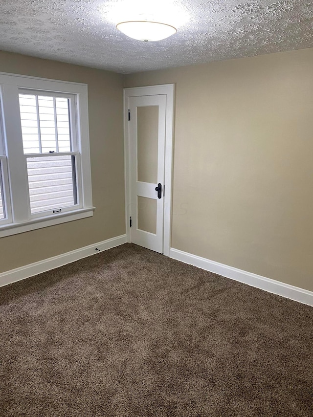 unfurnished room featuring carpet and a textured ceiling