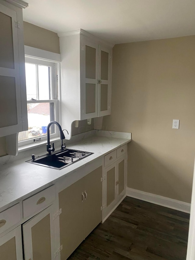 kitchen featuring dark hardwood / wood-style flooring, light stone countertops, sink, and white cabinets