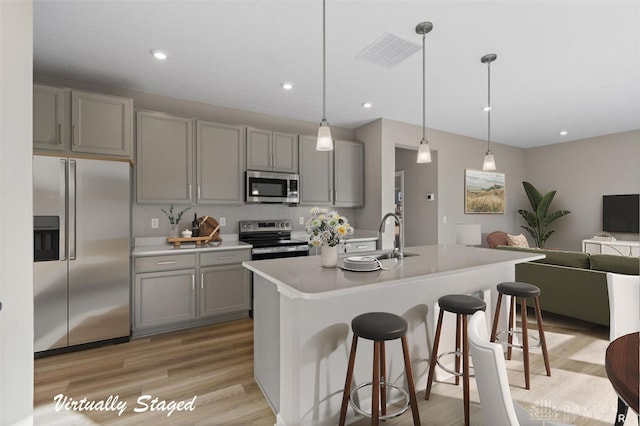 kitchen featuring appliances with stainless steel finishes, decorative light fixtures, gray cabinets, and sink