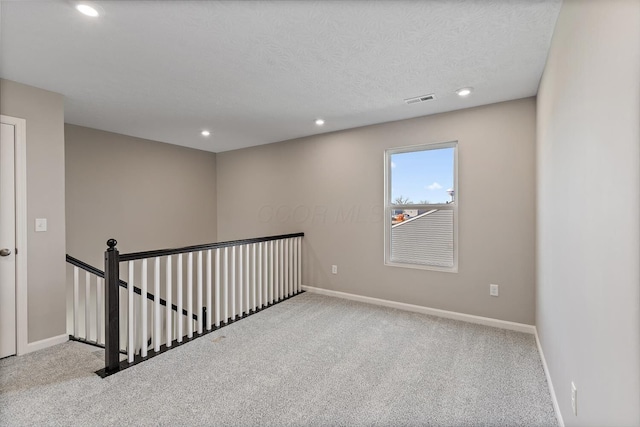 carpeted empty room featuring a textured ceiling