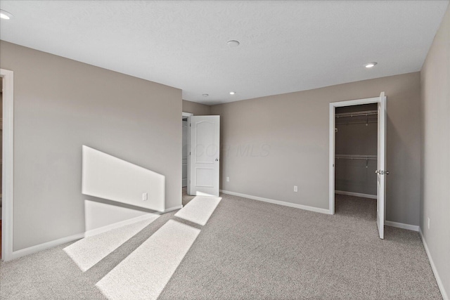 unfurnished bedroom featuring a spacious closet, light carpet, and a closet