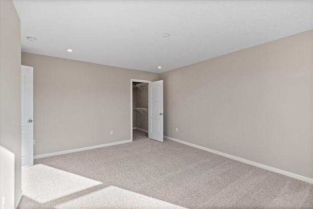 unfurnished bedroom featuring carpet, a walk in closet, and a closet