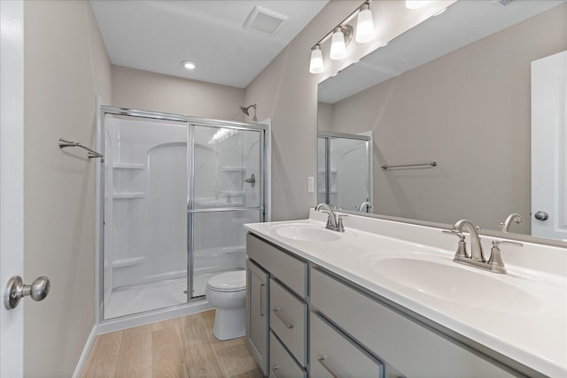 bathroom with hardwood / wood-style flooring, toilet, and a shower with shower door