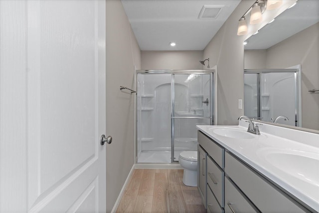 bathroom with hardwood / wood-style floors, vanity, a shower with shower door, and toilet