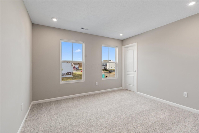 carpeted empty room featuring a textured ceiling