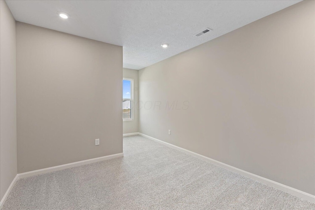 unfurnished room with light colored carpet and a textured ceiling