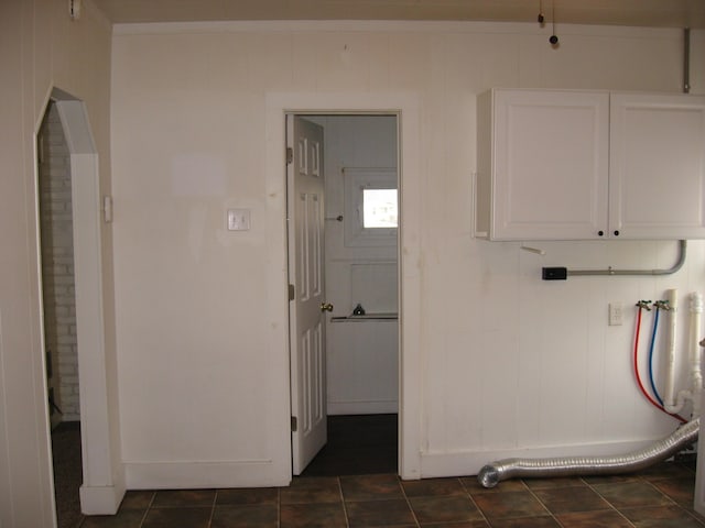 washroom featuring cabinets, dark tile patterned floors, and wood walls