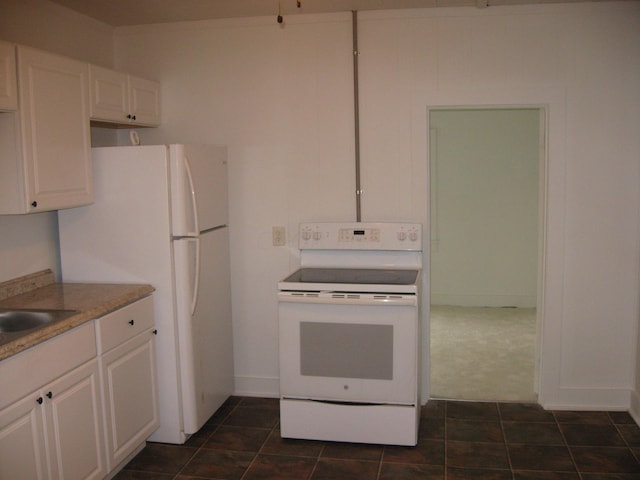 kitchen featuring white cabinets, white appliances, dark tile patterned flooring, and sink