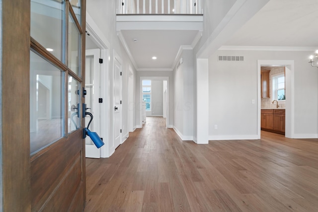 entryway featuring light wood-type flooring, crown molding, a healthy amount of sunlight, and sink