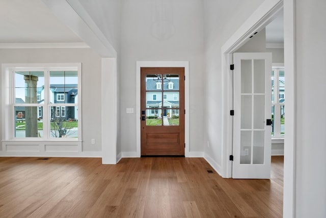 entrance foyer with a healthy amount of sunlight, ornamental molding, and light hardwood / wood-style flooring