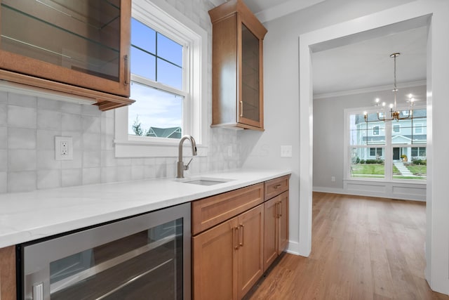 kitchen with sink, light hardwood / wood-style flooring, ornamental molding, tasteful backsplash, and beverage cooler