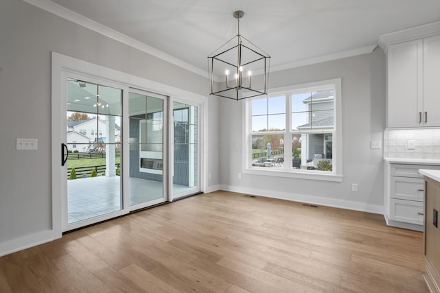 unfurnished dining area with crown molding, light hardwood / wood-style flooring, and a notable chandelier