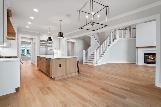 kitchen featuring ornamental molding, stainless steel appliances, a spacious island, light hardwood / wood-style floors, and hanging light fixtures