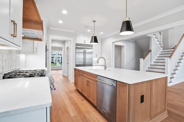 kitchen featuring pendant lighting, a center island with sink, sink, appliances with stainless steel finishes, and white cabinetry