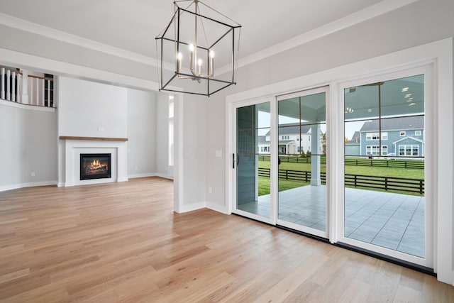 doorway featuring light wood-type flooring, ornamental molding, and a notable chandelier