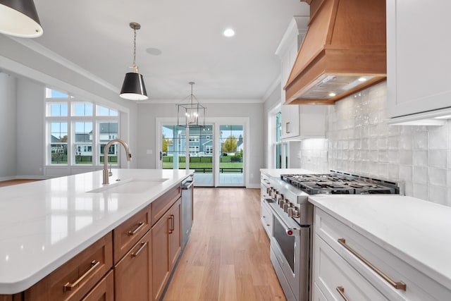 kitchen featuring white cabinets, custom range hood, sink, and appliances with stainless steel finishes