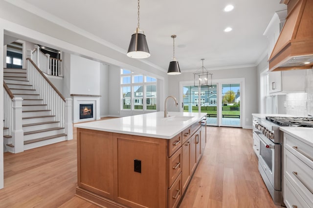 kitchen with white cabinetry, stainless steel stove, a kitchen island with sink, and custom exhaust hood