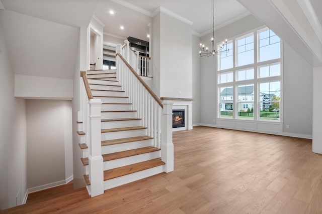 stairway featuring hardwood / wood-style floors, a notable chandelier, a healthy amount of sunlight, and a high ceiling