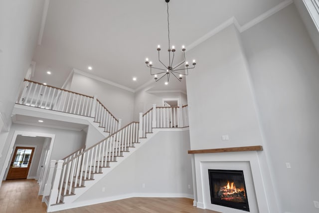 interior space with a chandelier, a high ceiling, light wood-type flooring, and ornamental molding