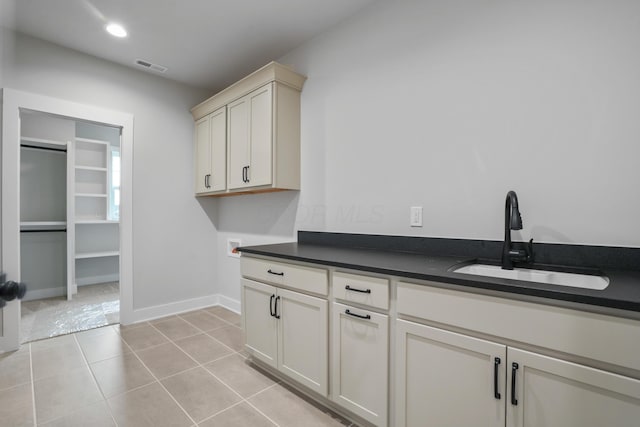 laundry room with hookup for a washing machine, sink, light tile patterned floors, and cabinets