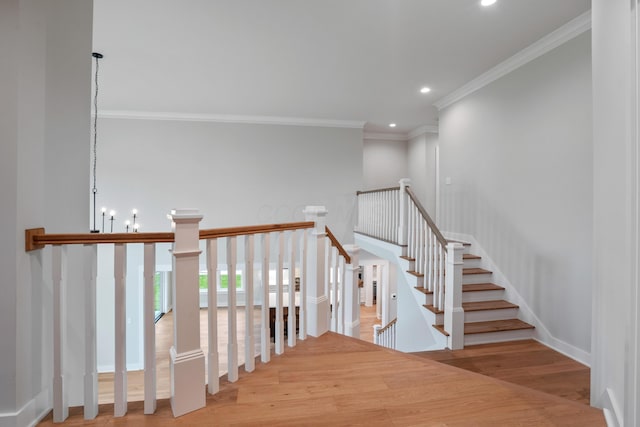 stairs with hardwood / wood-style flooring, crown molding, and an inviting chandelier