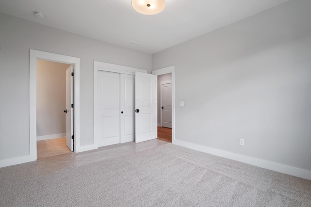 unfurnished bedroom with light carpet and a closet