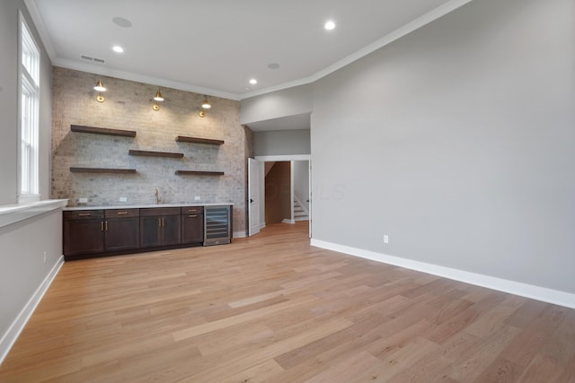 kitchen featuring dark brown cabinetry, light hardwood / wood-style flooring, beverage cooler, and ornamental molding