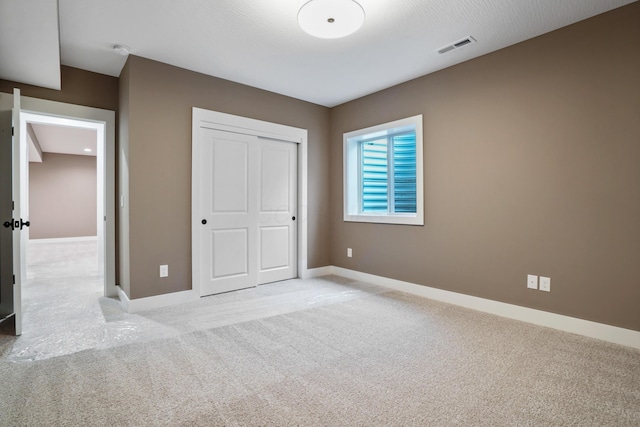 unfurnished bedroom featuring light carpet and a closet