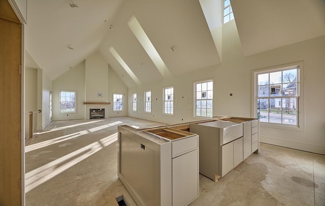 kitchen with white cabinets, a wealth of natural light, a center island, and high vaulted ceiling