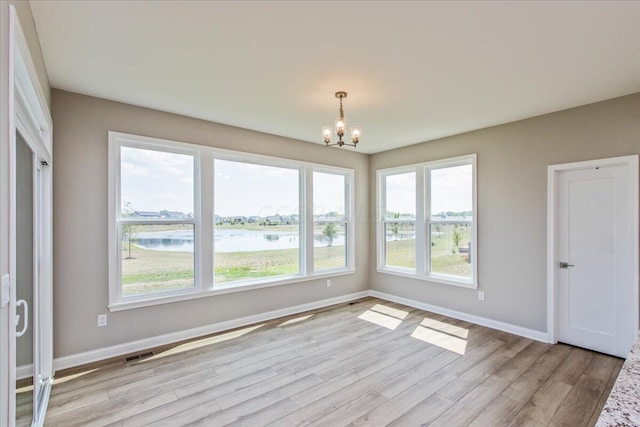 interior space with a water view, an inviting chandelier, and a healthy amount of sunlight