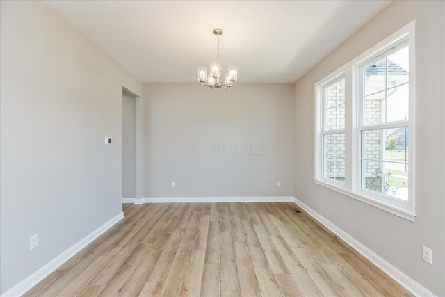 unfurnished room with light hardwood / wood-style flooring and an inviting chandelier