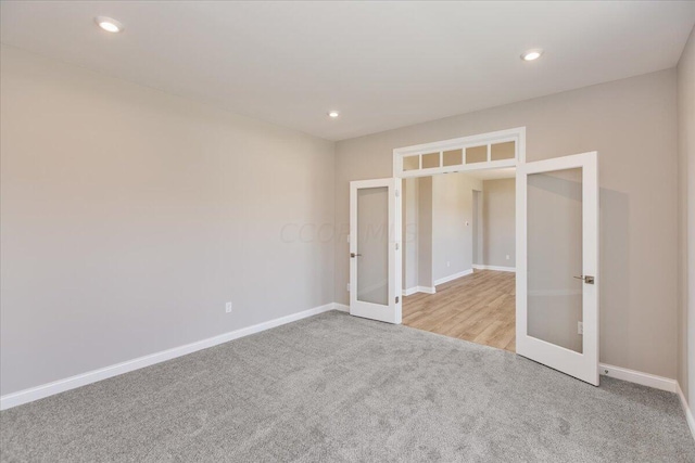 unfurnished bedroom featuring light carpet and french doors