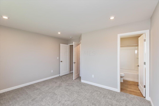 unfurnished bedroom with light carpet and connected bathroom