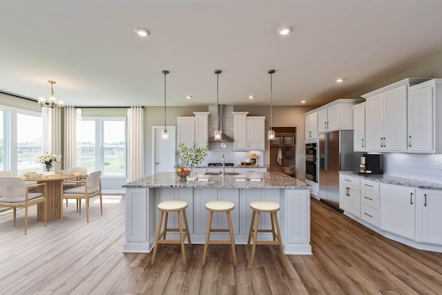 kitchen featuring wall chimney exhaust hood, hanging light fixtures, and tasteful backsplash