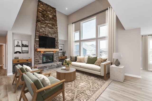 living room with a fireplace, a towering ceiling, and light hardwood / wood-style flooring