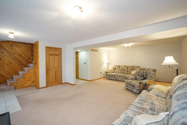 carpeted living room with wood walls and a textured ceiling