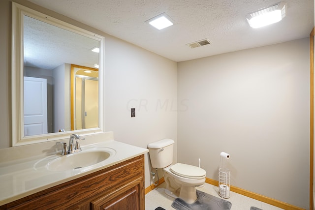 bathroom featuring vanity, a shower with shower door, a textured ceiling, and toilet