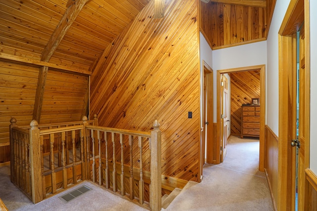 hall with wood walls, light carpet, and wooden ceiling