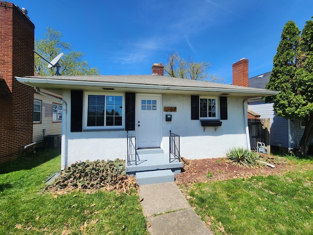 view of front of home with cooling unit and a front lawn