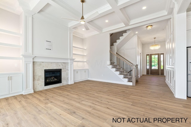 unfurnished living room with a tile fireplace, coffered ceiling, beamed ceiling, light wood-type flooring, and ornamental molding