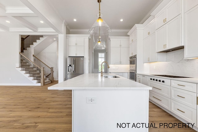 kitchen with a center island with sink, pendant lighting, white cabinets, and appliances with stainless steel finishes