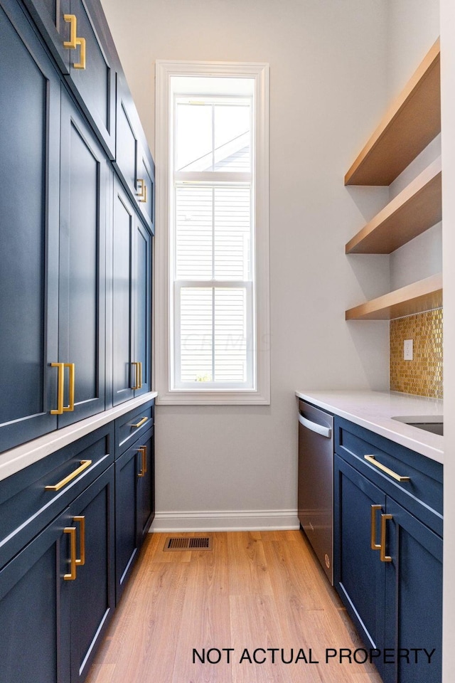 interior space featuring decorative backsplash, plenty of natural light, stainless steel dishwasher, and blue cabinets