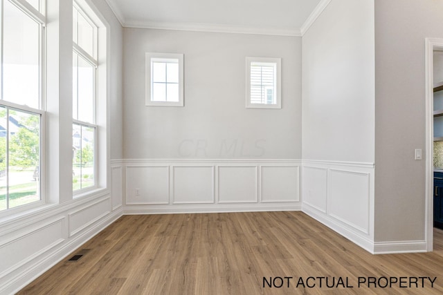 spare room with light hardwood / wood-style flooring, a wealth of natural light, and ornamental molding